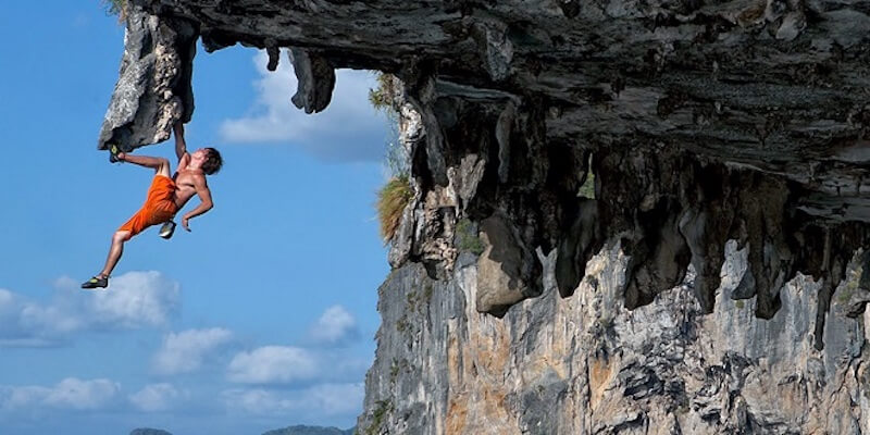 Uomo free climbing su roccia