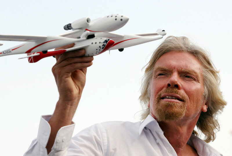 Foto di Richard Branson che solleva il modellino di un aeroplano
