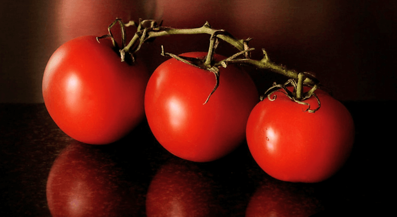Foto di tre pomodori su sfondo scuro